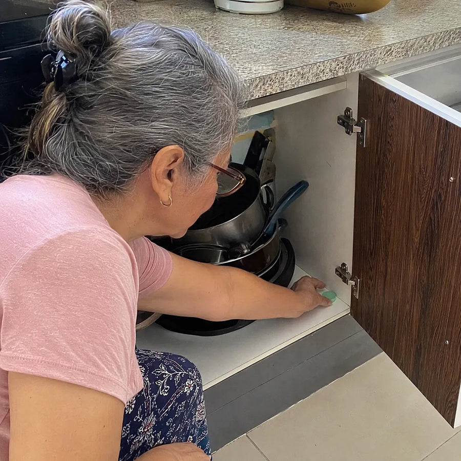 La mamá de Lorena coloca una pastilla Rinco dentro de un mueble de su cocina